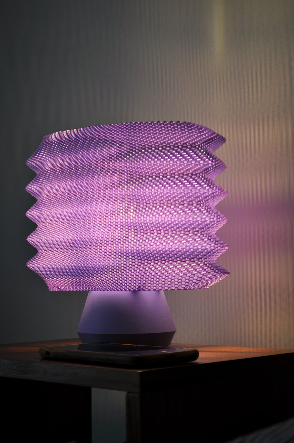 Lavender Bellows Weave Lamp illuminated on a nightstand