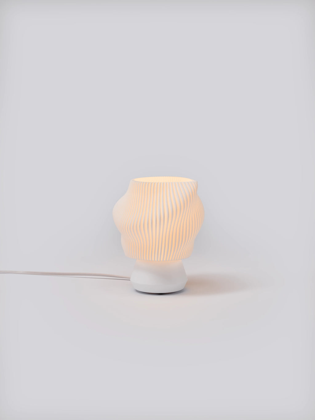White Dollop Lamp illuminated on a white studio background, showing pleated shade and soft glow