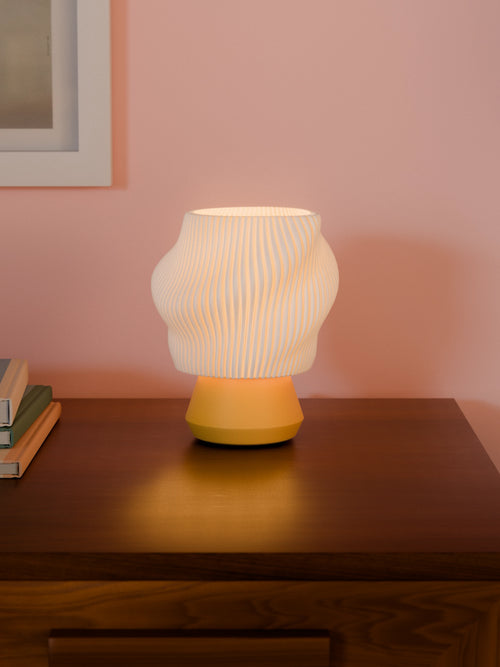 Yellow Dollop lamp illuminated on a table with books