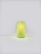 Mint green Nixie Lamp illuminated on a white studio background, showing colorful glow