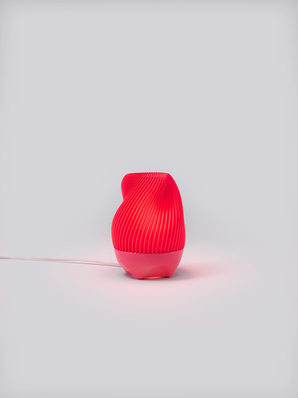 Pink Tama Lamp illuminated on a white studio background, showing pleated shade and colorful glow