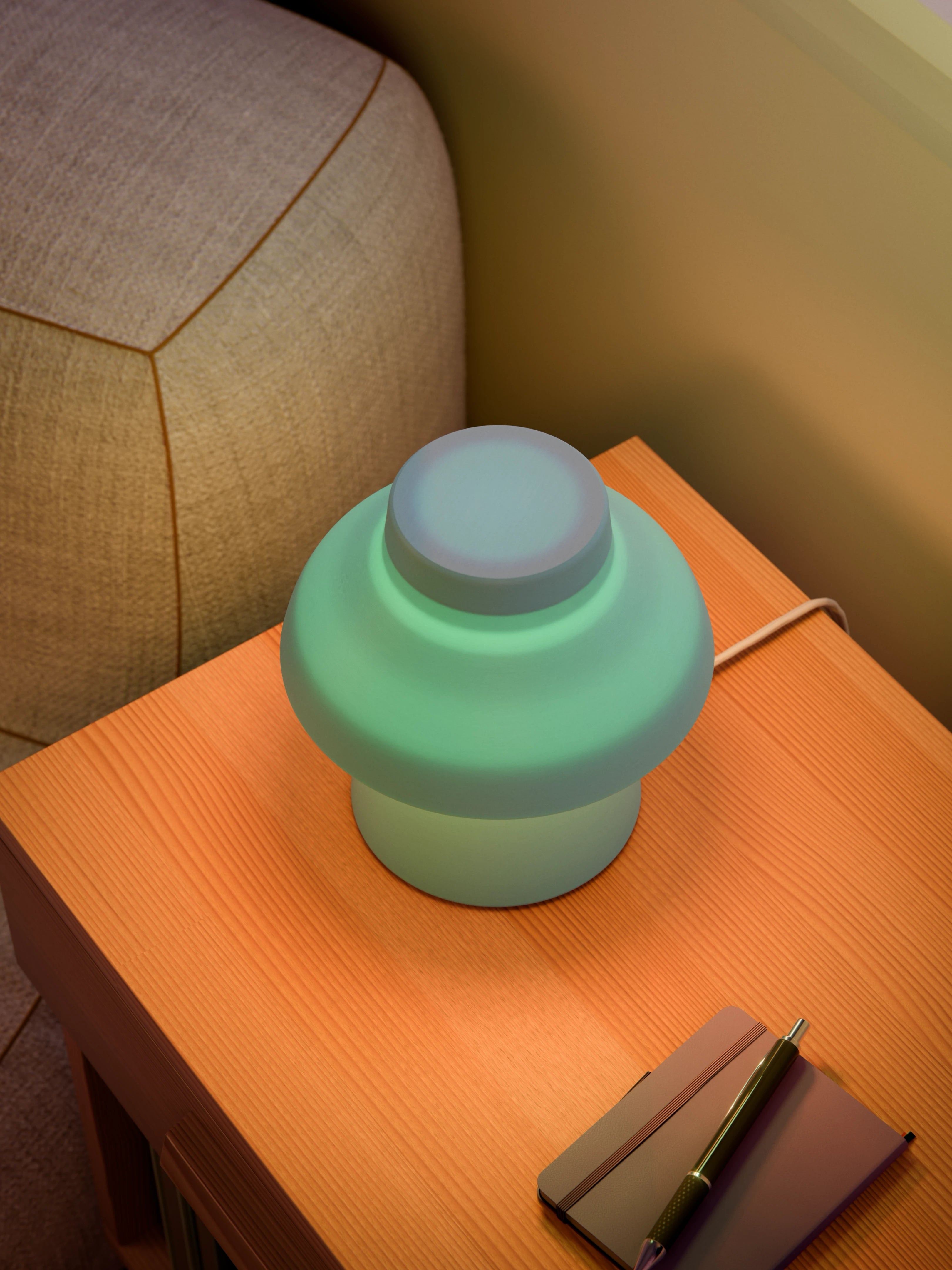 Light blue Zen Lamp illuminated on a living room side table with a pen an notebook, viewed from above.
