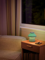 Light blue Zen Lamp illuminated on a living room side table with a pen an notebook.
