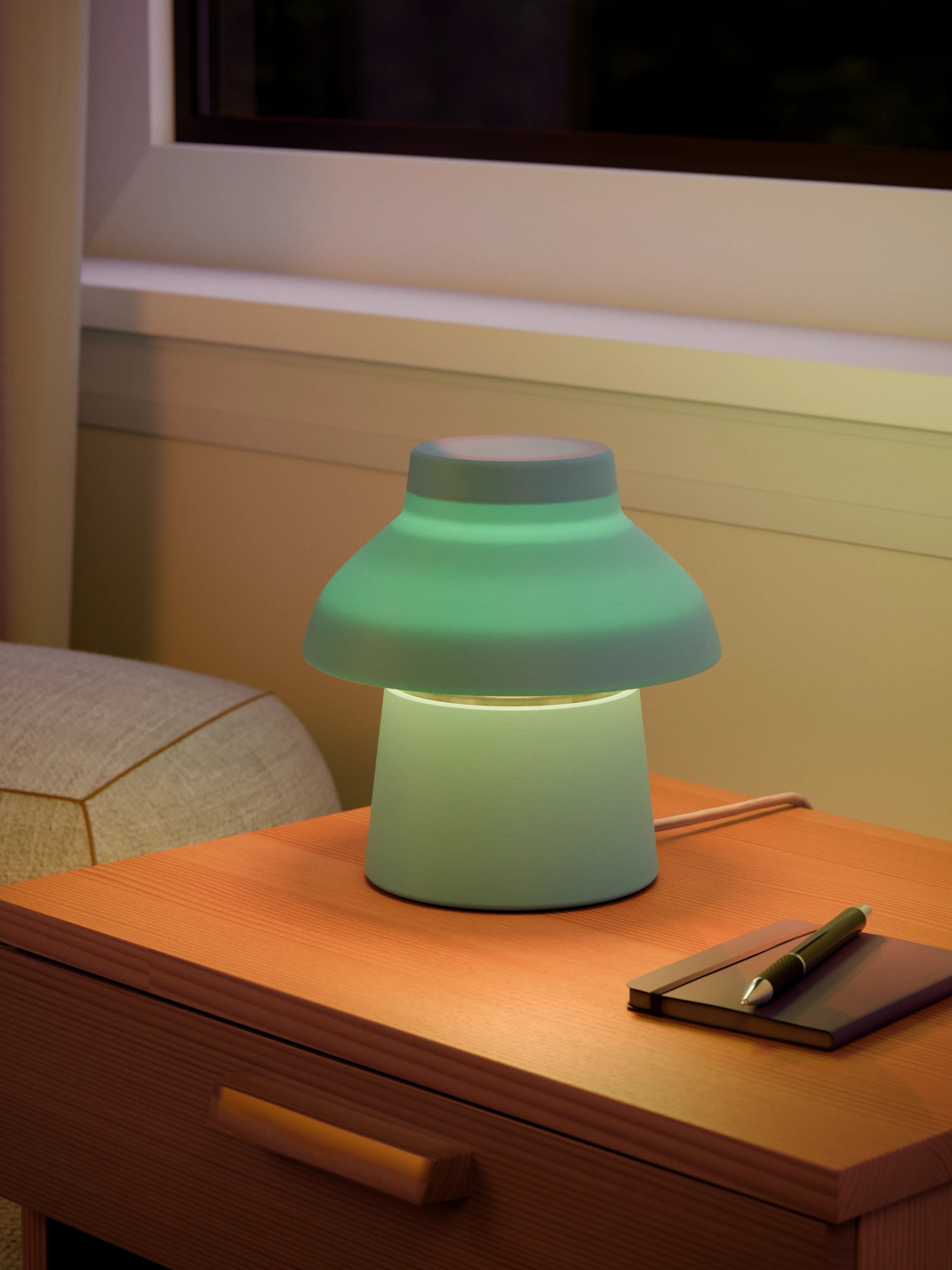 Light blue Zen Lamp illuminated on a living room side table with a pen an notebook.