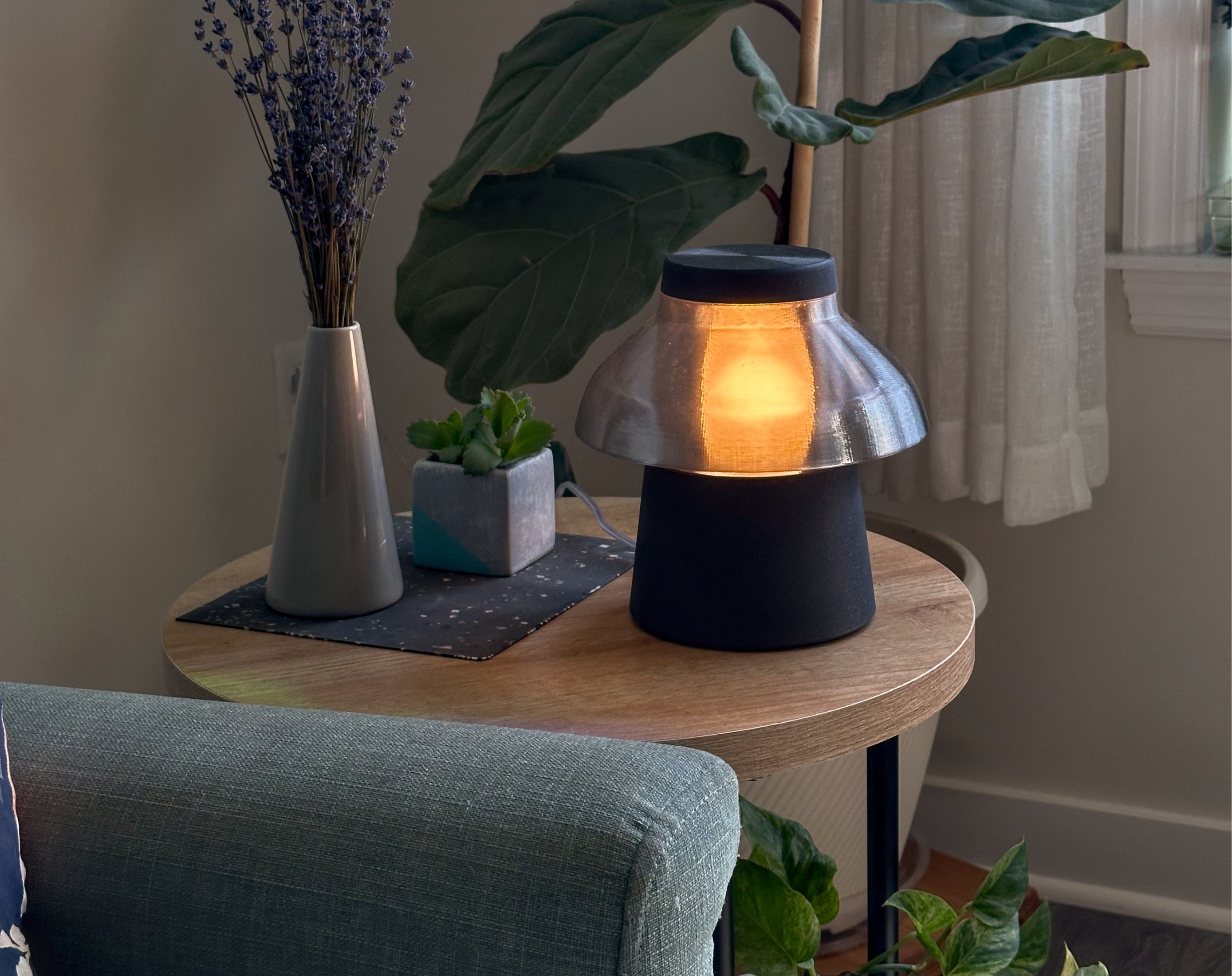 Transparent smoke gray Zen lamp illuminated on a living room side table, styled with plants